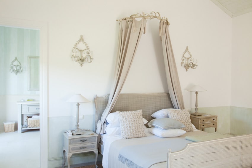 Classic bedroom with candle wall sconces, pillows, nightstand, headboard, and footboard