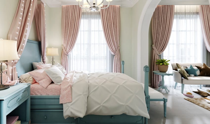 Classic bedroom with chalk paint bed frame, comforter, pillows, nightstand, lamp, couch, pink curtains, and windows