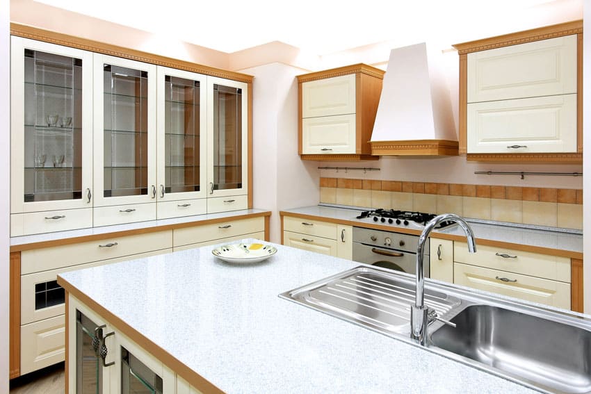 Classic kitchen with reglazed countertop, glass cabinets, tile backsplash, range hood, and stove