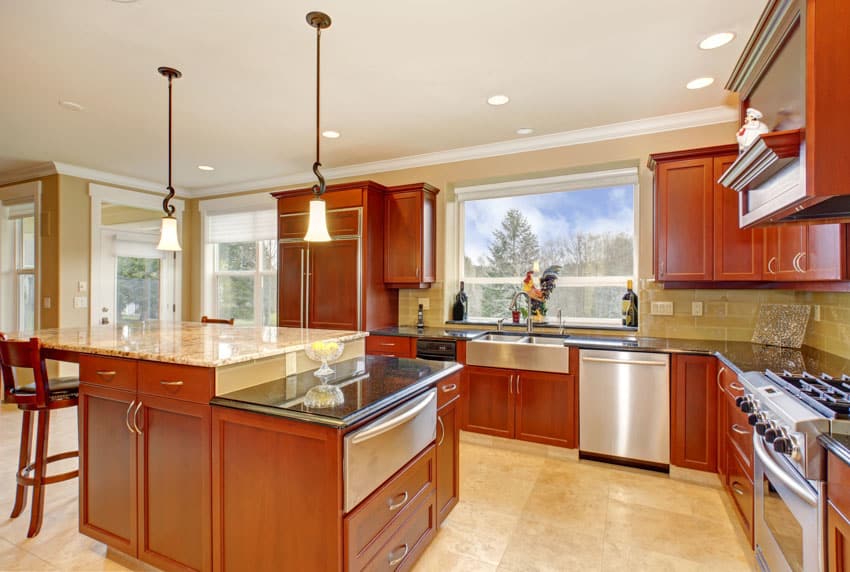 Classic kitchen with wood cabinets, dishwasher, travertine tile floor, countertops, pendant lights, backsplash, and windows