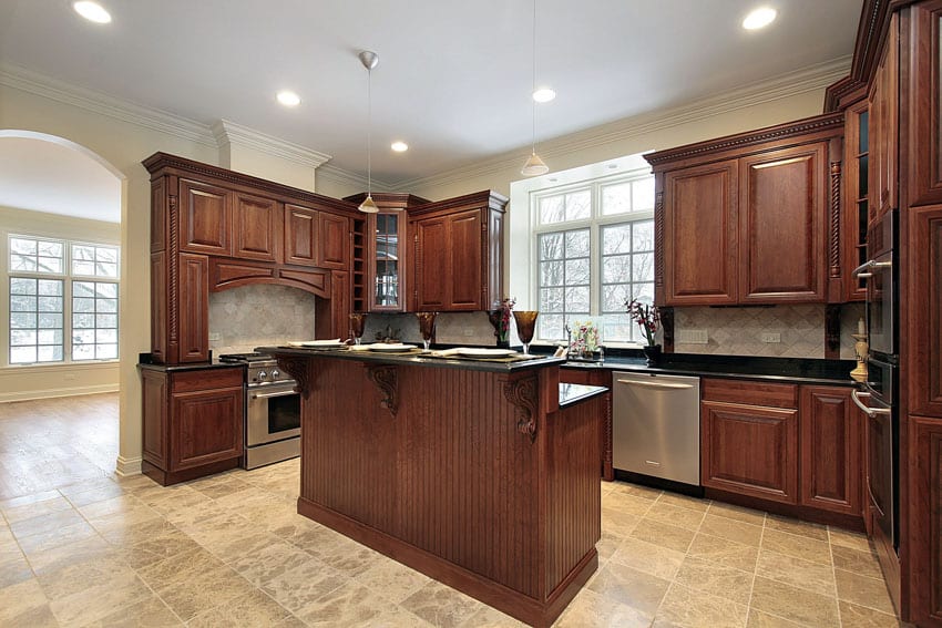 Rustic kitchen with wood cabinets, travertine tile floor, island, windows, countertop, backsplash, and ceiling lights