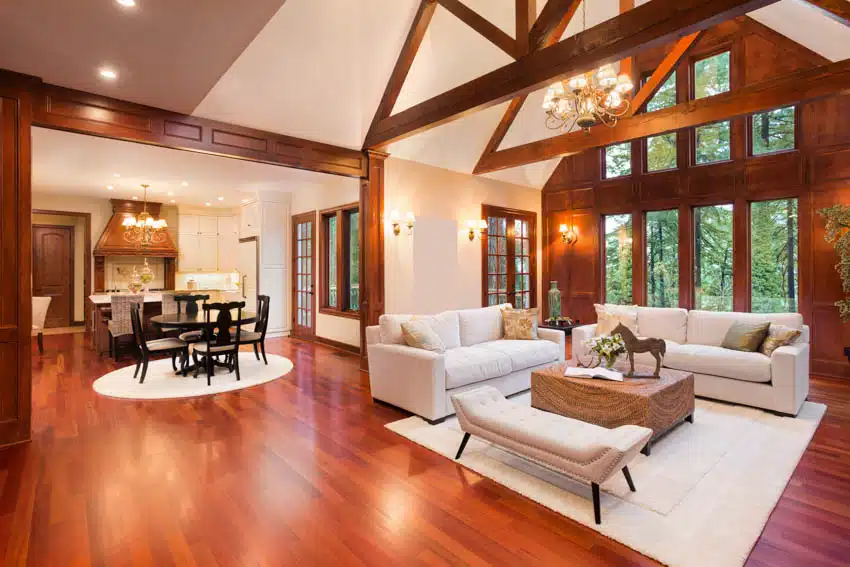 Classic living room with redwood softwood flooring, high ceiling, sofa, rug, coffee table, windows, and dining area
