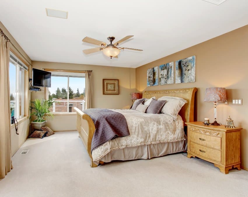 Classic master bedroom on tan and cream interior with wooden furniture and nice bedding