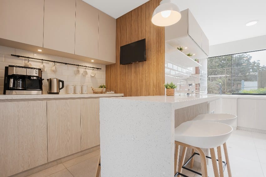 Clean kitchen with white and beige tones features beige cabinets and island with stools