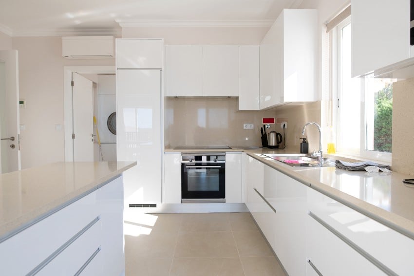 Clean look modern kitchen with polyurethane cabinets, beige stone counter top and ceramic tiled floor