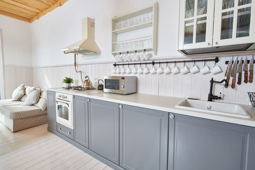Coastal kitchen with painted pressed wood cabinets, countertop, backsplash, and range hood