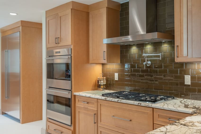 Contemporary kitchen with copper glass backsplash, range hood, countertop, stove, and oven