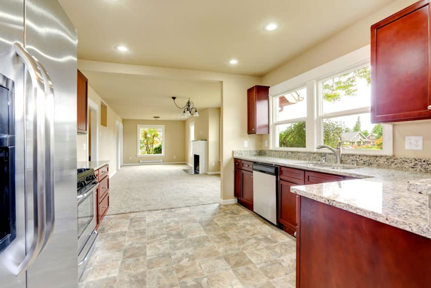 Contemporary kitchen with silver travertine tile floor, countertop, refrigerator, wood cabinets, and window