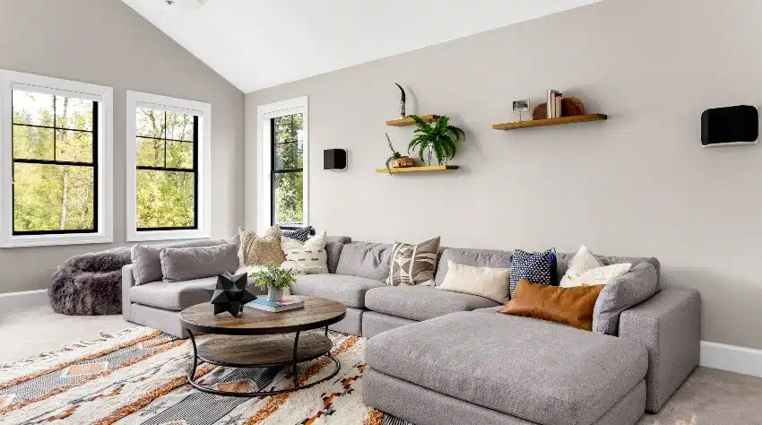 Contemporary living room with open floor plan concept in white and gray colors featuring large sofa, round coffee table, boho floor carpet and wall decors