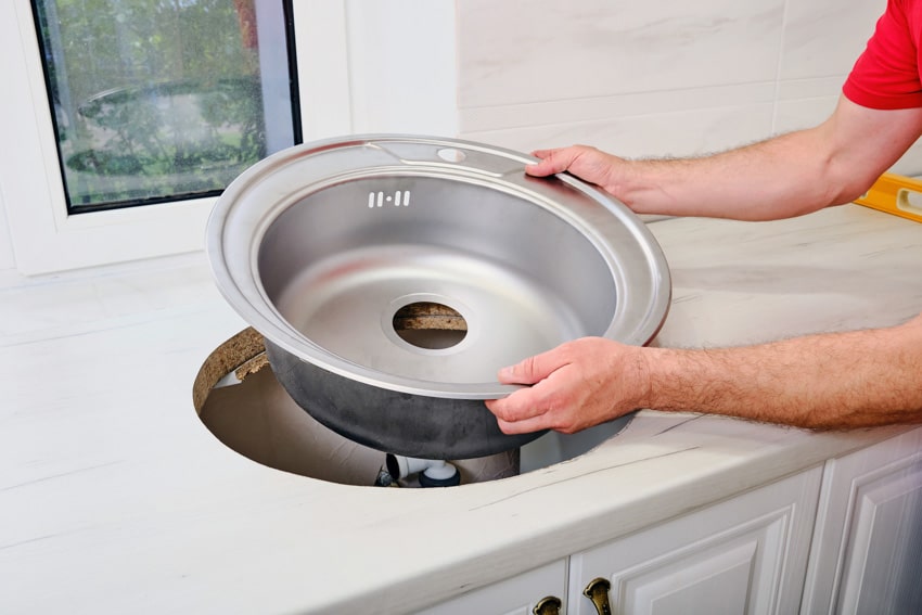 Contractor installing sink on kitchen countertop 