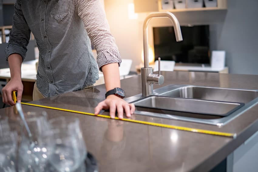 Contractor measuring countertop for remodel planning purposes