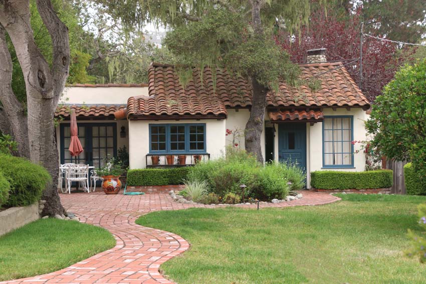 Cottage house with brick tile walkway, orange shingle roof, and chimney