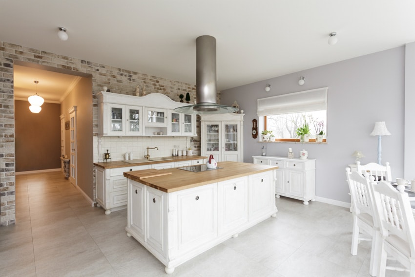 Kitchen with wood countertops, range hood, freestanding cabinets, backsplash and windows
