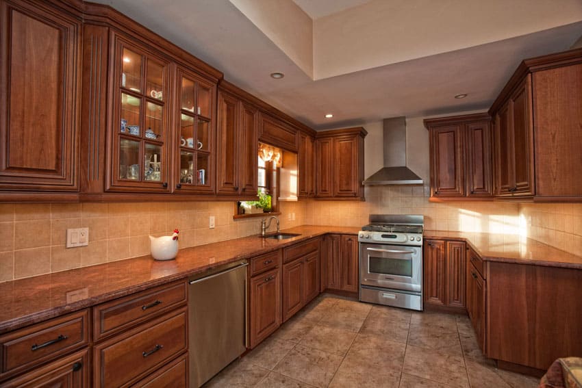 Craftsman kitchen with cypress cabinets, tile backsplash, countertops, dishwasher, oven, stove, and range hood