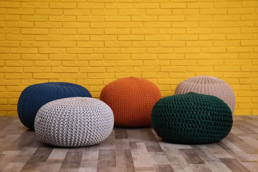 Different pouf shapes in a room with yellow brick wall
