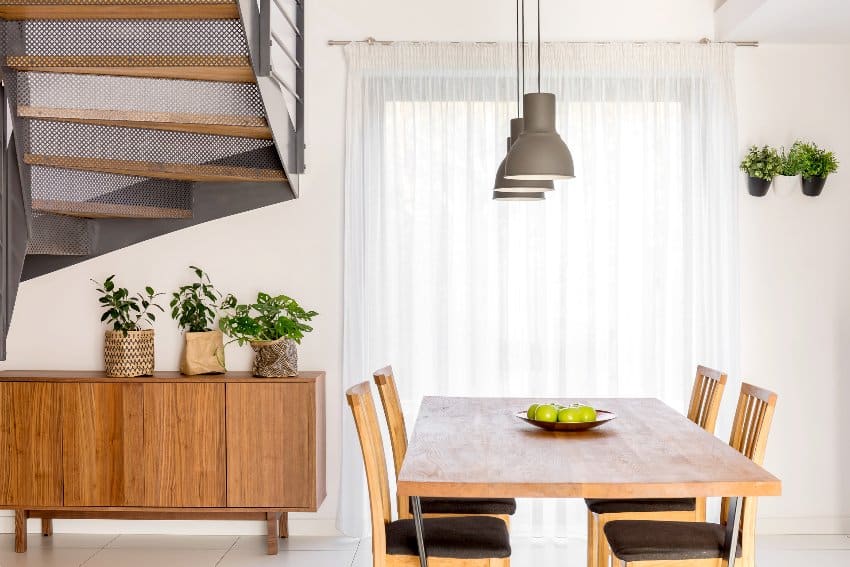 Dining room with wooden table, lamp, dresser and stairs