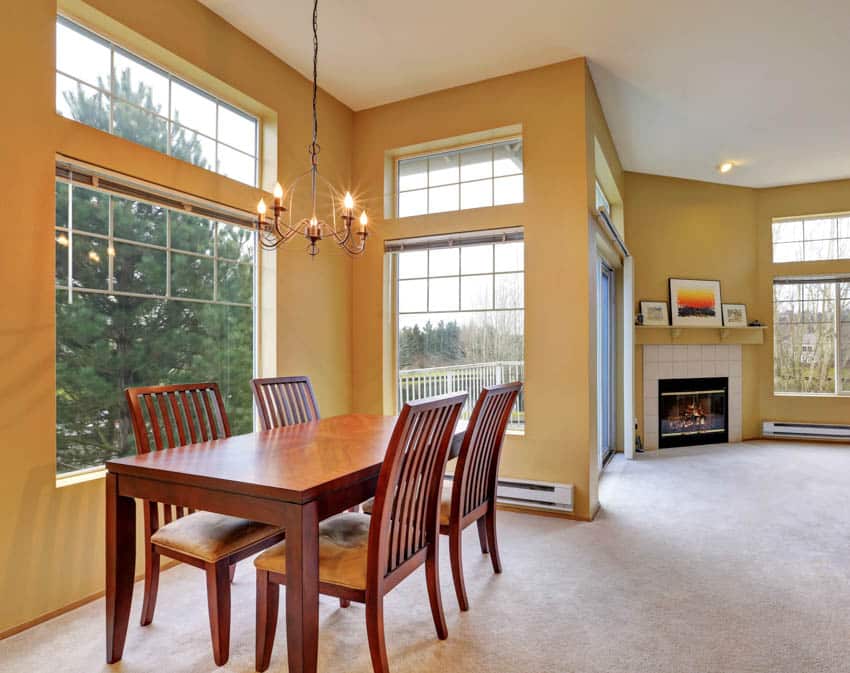 Dining space with table, chairs, chandelier, fireplace, and windows