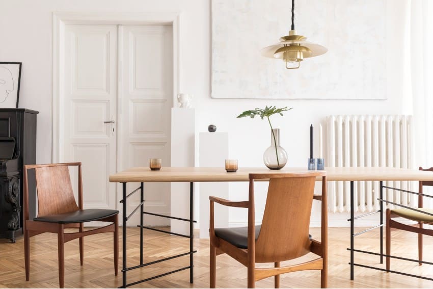 Eclectic and elegant dining room interior with design sharing table, chairs, and gold pendant lamp