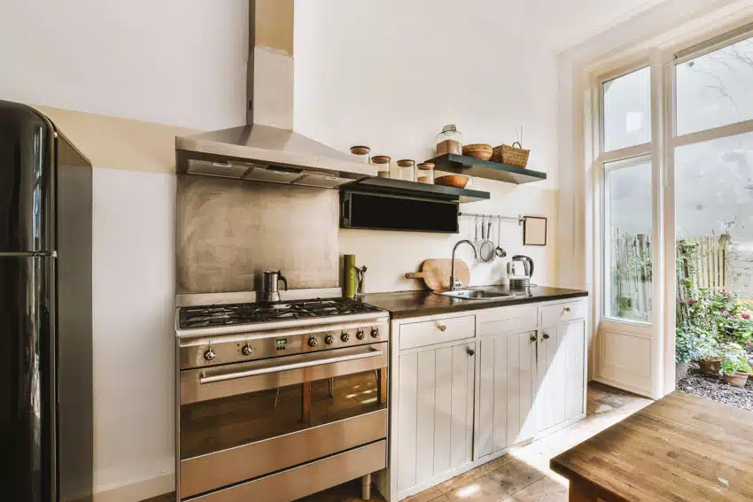 Farmhouse Kitchen With Copper Sheet Backsplash White Cabinets Countertop Stove Oven Range Hood And Glass Door Is .webp