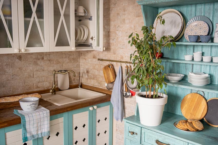 Farmhouse kitchen with multipurpose freestanding cabinet, wood countertop, glass cabinet, sink, and travertine backsplash