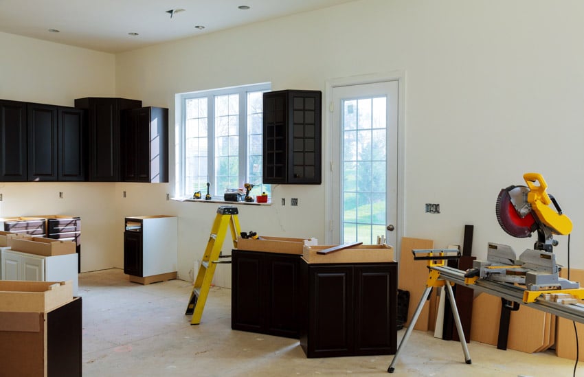 Home kitchen being remodeled with black cabinets, windows, and handyman construction tools