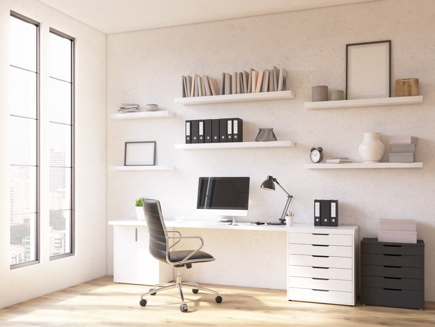 Home office with chair, desk, computer, floating shelves, filing cabinets with drawers, lamp, and windows