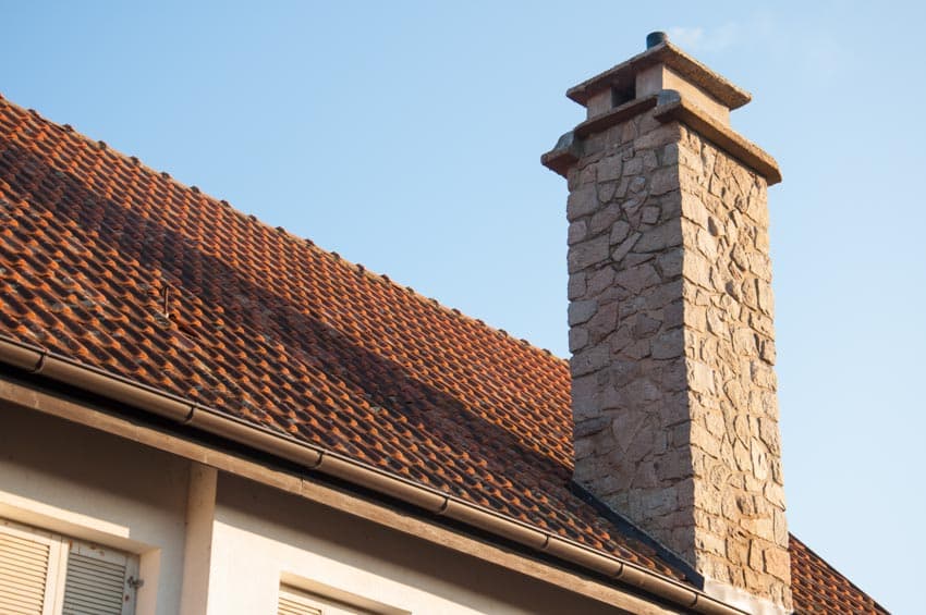 House exterior with orange shingle roof and stone chimney