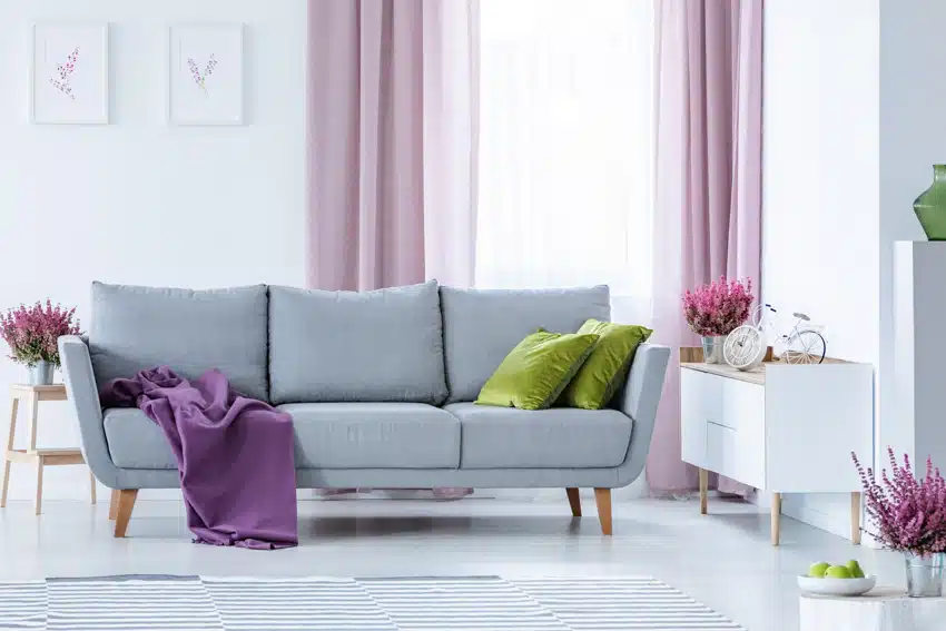 Living room with modern pink curtain colors, white walls, sheer liner, gray sofa, pillows, and console table