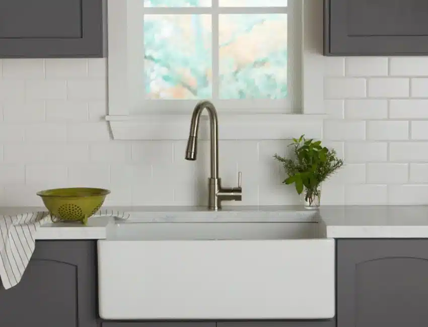 Kitchen with farmhouse sink, faucet, cabinets, and matte subway tile backsplash