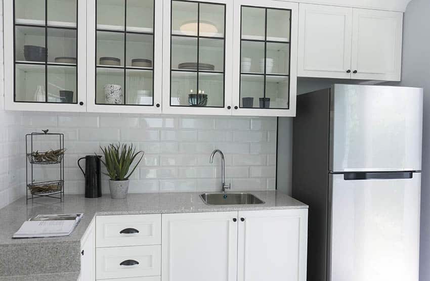Kitchen with glass front cabinets above sink white tile backsplash