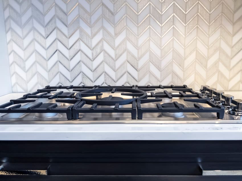Kitchen with metal chevron design tile backsplash and stove