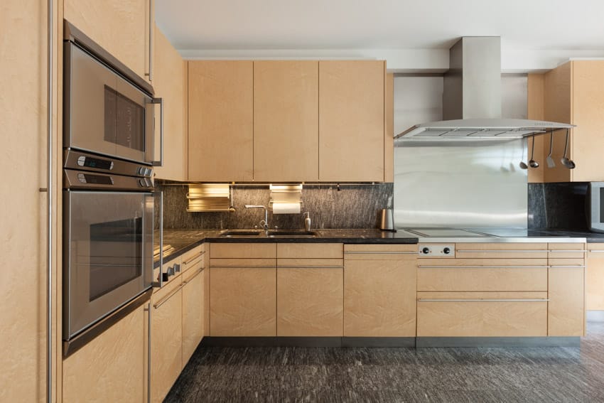 Kitchen with rubberwood cabinets, backsplash, range hood, countertop, and oven