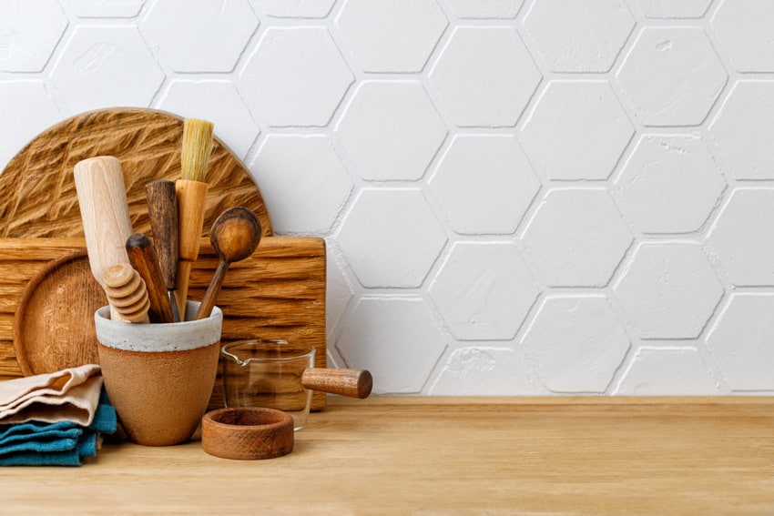 Kitchen with white hexagon matte backsplash tile, wood countertop, and kitchenware items