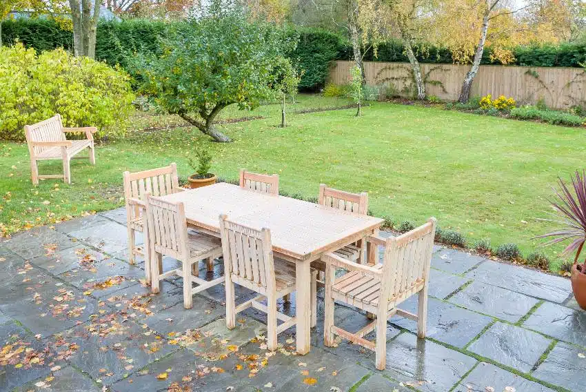 Large back garden in autumn with outdoor ash wood furniture on patio terrace