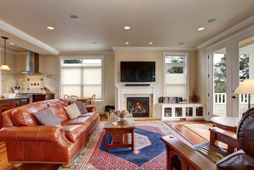 Open layout room with leather couch, fireplace, recessed lighting and glass doors