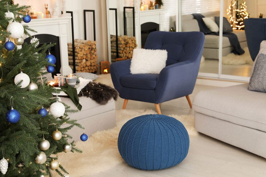 Living room with blue accent chair, floor pouf, mirror, and fireplace