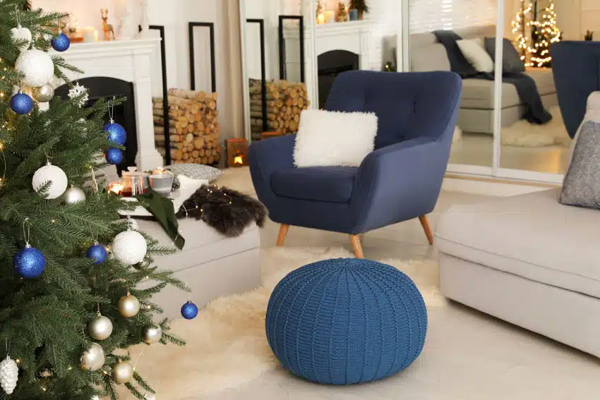 Living room with blue accent chair, floor pouf, mirror, and fireplace