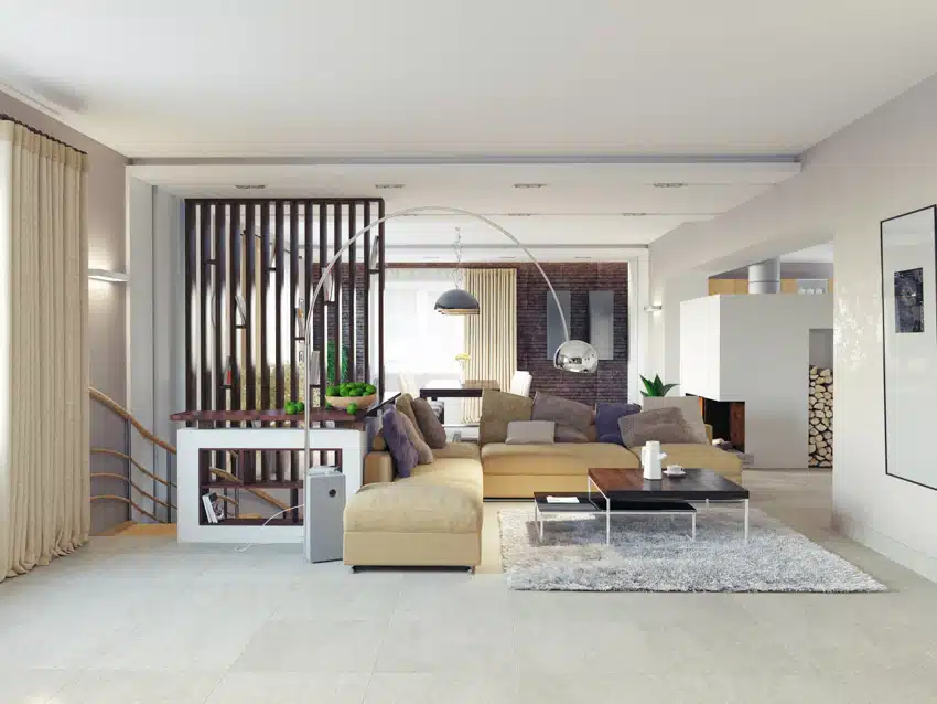 Living room with matte porcelain tile floor, ottoman, coffee table, sofa, wood slat divider, and rug