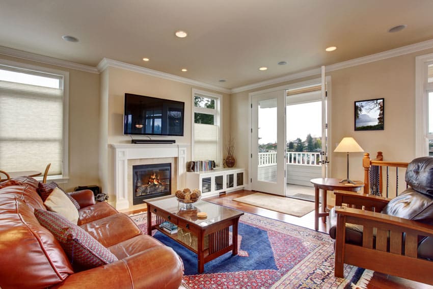 Room with leather couch, television, fireplace and glass door