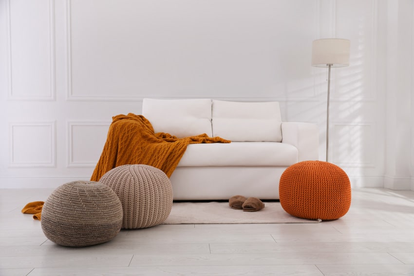 Living room with poufs, couch, white walls, and floor lamp