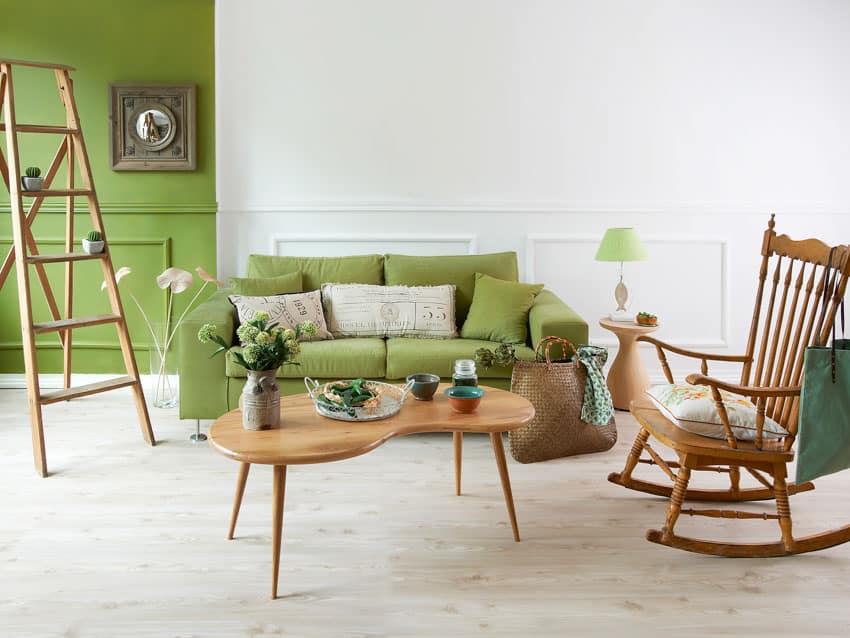 Living room with rocking chair, green couch, coffee table, side table, lamp, and wood floor