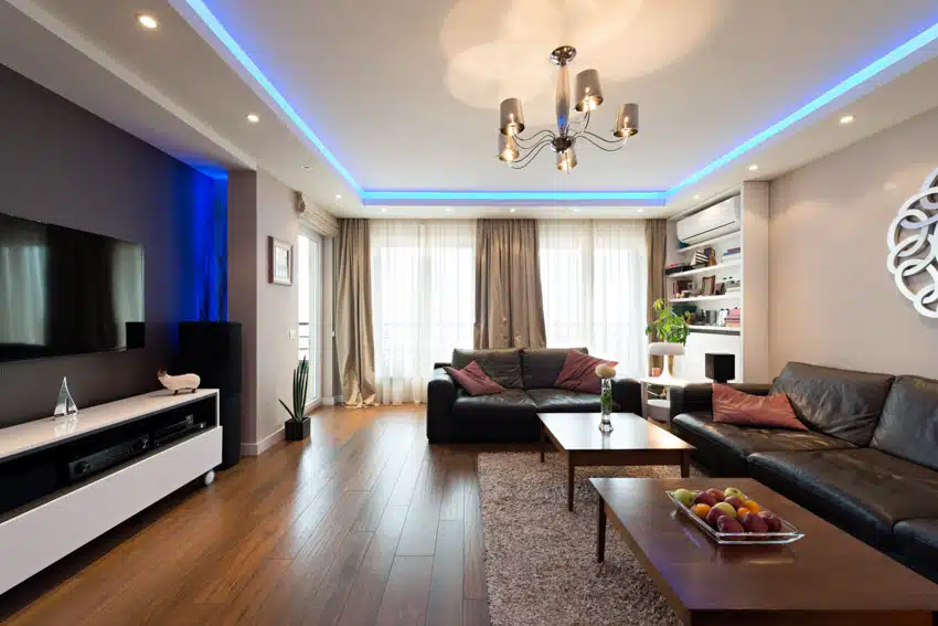 Room with blue backlit ceiling, television, two center tables and rug