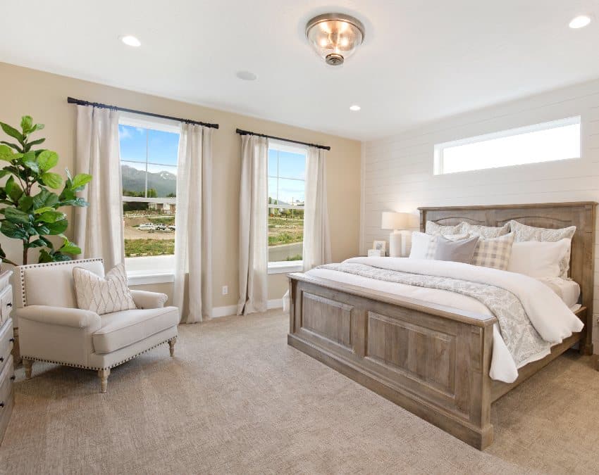 Luxurious new beige bedroom with white and brown furniture and large oversized windows