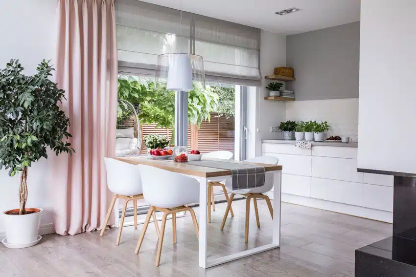 Minimalist dining room with white walls, pink curtains, table, chairs, wood flooring, and pendant lighting