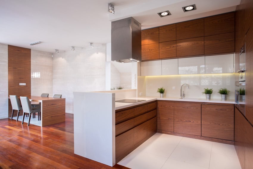 Minimalist kitchen with wood refaced cabinets, backsplash, countertop, and range hood