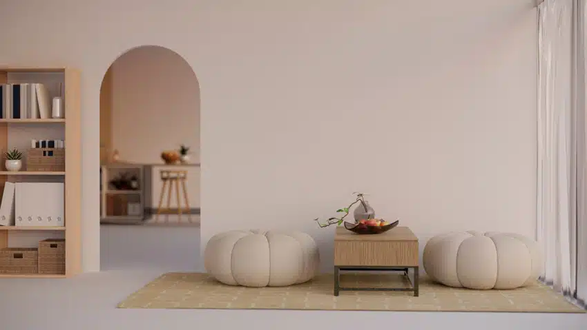Minimalist living room with pastel walls, pouf, rug, bookshelves, and window curtain