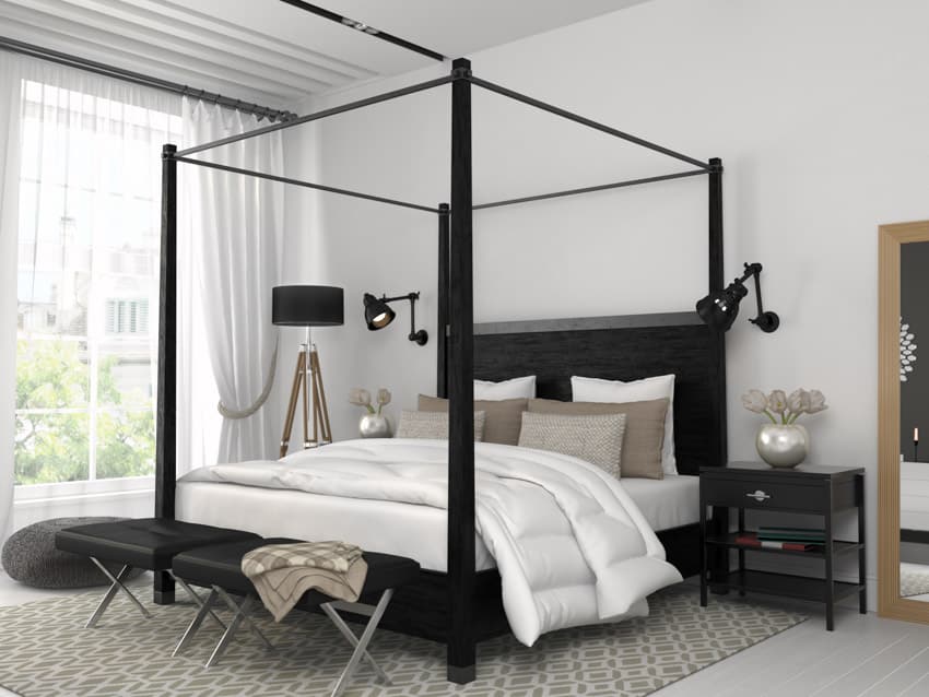 Four poster bed, carpet, white comforter and black floor lamp