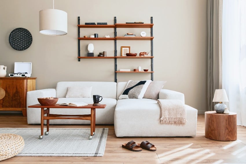 Modern interior with design modular beige sofa, coffee table, stylish furniture, shelf, decoration and elegant personal accessories