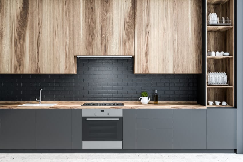 Modern kitchen with bookmatch wood cabinet panels, matte black tile backsplash, countertop, oven, and shelves