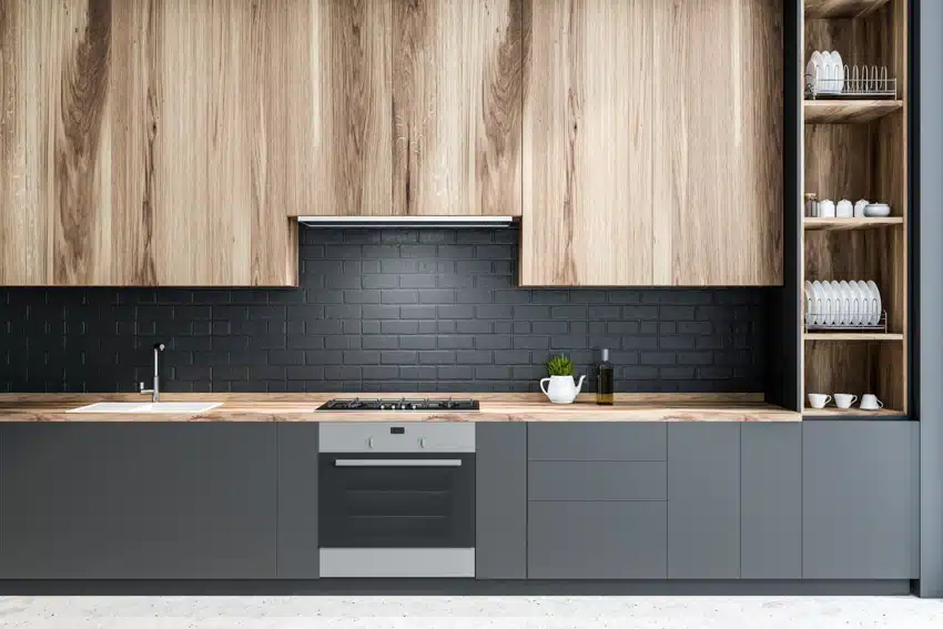 Modern kitchen with bookmatch wood cabinet panels, matte black tile backsplash, countertop, oven, and shelves